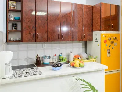 a kitchen with wooden cabinets and a bowl of fruit on a counter at Hostel White Town in Belgrade
