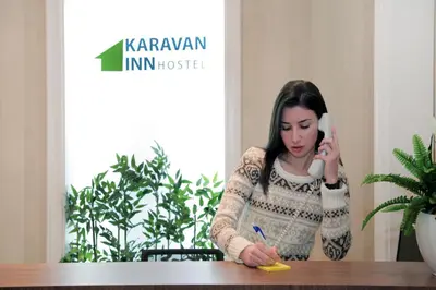 a woman talking on a phone and writing on a table at Hostel Karavan Inn in Belgrade