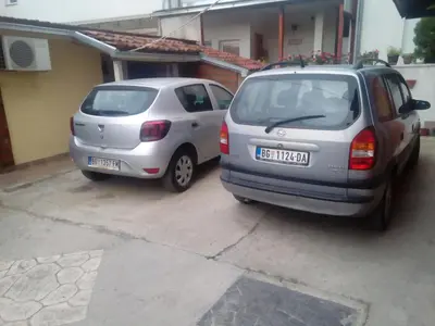 two cars parked next to each other in a parking lot at Guest house Mirijevski Konak in Belgrade