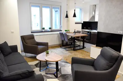 a living room with chairs and a table and a kitchen at Apartments Belvedere in Belgrade
