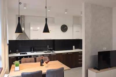 a kitchen with a wooden table with chairs and a clock at Apartments Belvedere in Belgrade