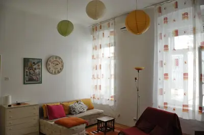 a living room with a couch and a clock on the wall at Apartment Angie in Belgrade