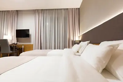 a hotel room with two white beds and a desk at Hotel Orasac Garni in Belgrade