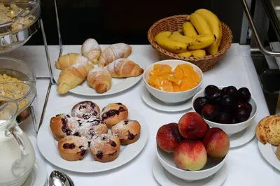 a table with plates of food and bowls of fruit at Hotel Orasac Garni in Belgrade