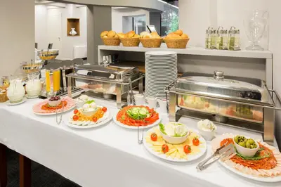 a buffet with plates of food on a counter at Hotel Orasac Garni in Belgrade