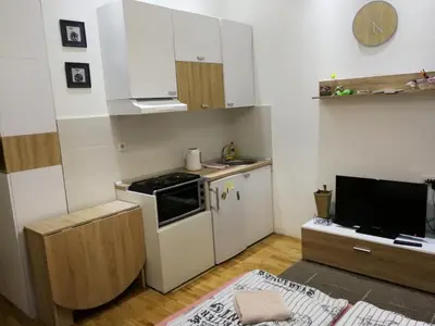 a small kitchen with white cabinets and a television at Imperia Apartments in Belgrade