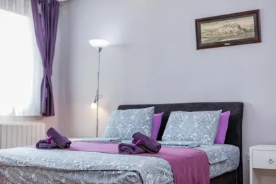 a bedroom with a bed with purple and blue pillows at Apartment Gloria in Belgrade