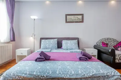 a bedroom with a large bed and a chair at Apartment Gloria in Belgrade
