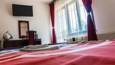 a bedroom with a bed with red sheets and a window at Apartmani 