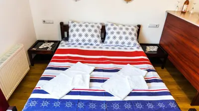 a bed with a red white and blue blanket and pillows at Apartmani 