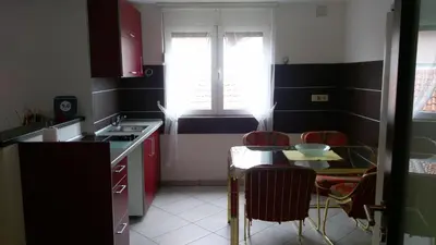 a kitchen with red cabinets and a table and a window at Apartment Krsmanovic in Arandjelovac