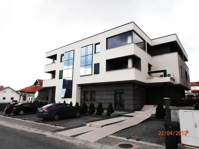 a large white building with cars parked in front of it at Apartment Krsmanovic in Arandjelovac