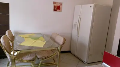 a table with chairs and a white refrigerator in a kitchen at Apartment Krsmanovic in Arandjelovac