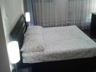 a bedroom with a bed with a white comforter and two lights at Apartment Dok in Belgrade