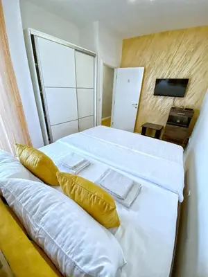a bedroom with a bed with white sheets and yellow pillows at Pleasure Lux1 Apartment in Belgrade