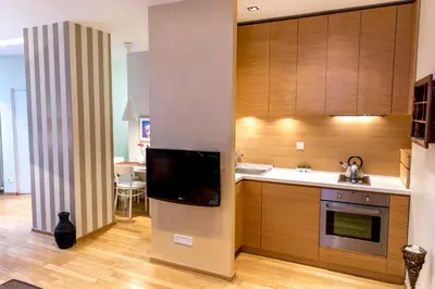 a kitchen with wooden cabinets and a flat screen tv at Apartment Centro in Belgrade