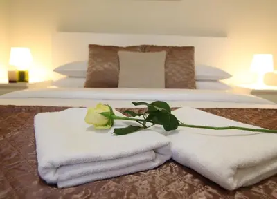 a hotel room with two beds with towels and a rose at Apartment Centro in Belgrade