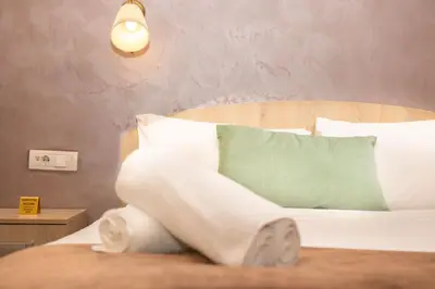 a bed with white sheets and a green pillow at Skadarlija Suites in Belgrade
