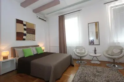 a bedroom with a bed with green pillows and two chairs at New Belgrade Apartment IN in Belgrade