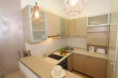 a kitchen with wooden cabinets and a sink and lights at New Belgrade Apartment IN in Belgrade