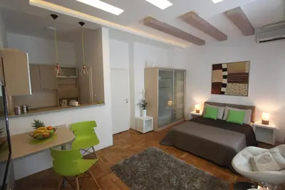 a bedroom with a bed and a table and green chairs at New Belgrade Apartment IN in Belgrade