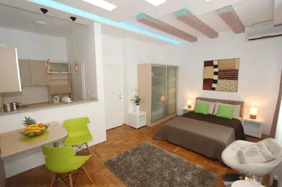 a bedroom with a bed and a table and a kitchen at New Belgrade Apartment IN in Belgrade