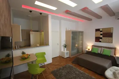 a bedroom with a bed and a table and green chairs at New Belgrade Apartment IN in Belgrade