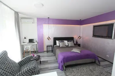 a purple bedroom with a bed and a chair at New Belgrade Apartment ARENA in Belgrade