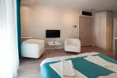 a bedroom with a bed and two chairs and a television at Apartment Savamala Art in Belgrade