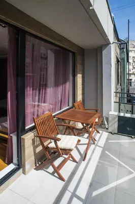 two chairs and a wooden table on a balcony at Apartment Savamala Art in Belgrade