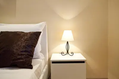 a lamp on a night stand next to a bed at Feel Belgrade Bohemian Apartment in Belgrade