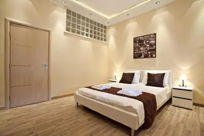 a bedroom with a large bed with two lamps and a door at Feel Belgrade Bohemian Apartment in Belgrade