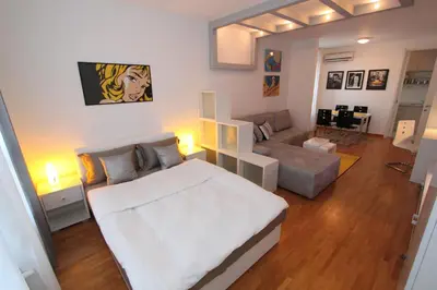 a bedroom with a large white bed and a couch at New Belgrade apartment Neven, parking 5 evra dan in Belgrade