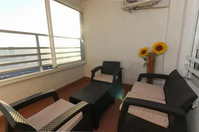 a living room with chairs and a vase of sunflowers at New Belgrade Apartment Lavina, parking 5 evra dan in Belgrade