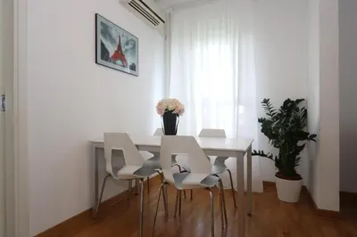a dining room table with white chairs and a vase of flowers at New Belgrade Apartment Belville, parking 5 evra dan in Belgrade