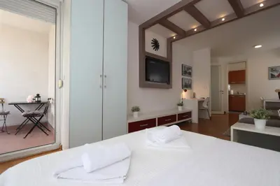a bedroom with a white bed and a living room at New Belgrade Apartment Belville, parking 5 evra dan in Belgrade