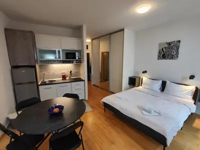 a bedroom with a bed and a table and a kitchen at Belle Apartments-Elegance Apartments in Belgrade