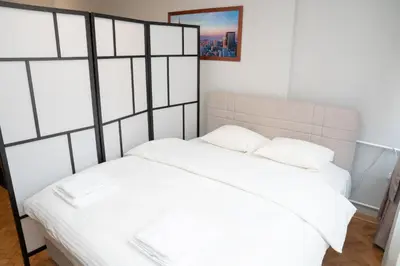 a bedroom with a white bed with white sheets at Tommy Apartment in Belgrade