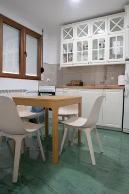a kitchen with a wooden table and white chairs at Tommy Apartment in Belgrade