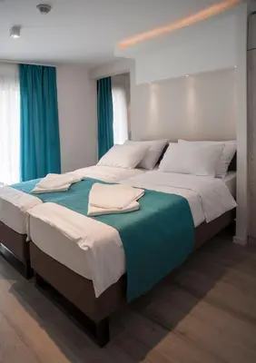 two beds in a bedroom with blue curtains at Apartments Villa Savamala in Belgrade