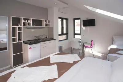 a bedroom with a bed and a kitchen with a table at Apartments Villa Savamala in Belgrade