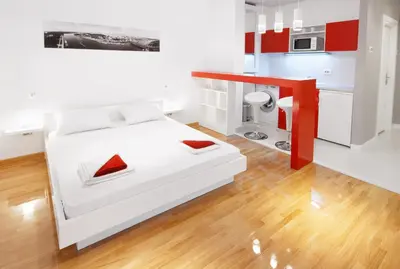 a bedroom with a white bed and a kitchen at Downtown Belgrade Apartments - CHERRY in Belgrade