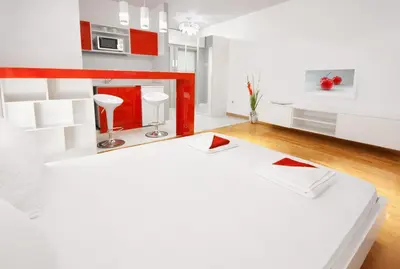 a kitchen with red and white cabinets and a bed in a room at Downtown Belgrade Apartments - CHERRY in Belgrade