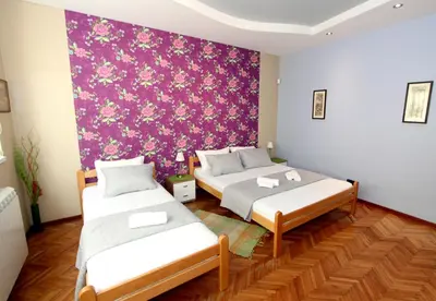 two beds in a room with a purple wall at Sneki Apartment in Belgrade