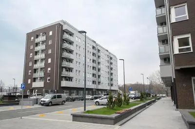 a parking lot with cars parked in front of a building at Apartman Cezar in Belgrade