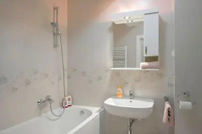 a bathroom with a sink and a bath tub and a mirror at Apartman Cezar in Belgrade