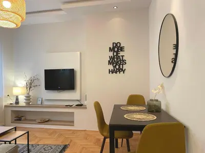 a dining room with a table and chairs and a tv at City Break Apartments Klishe Zen in Belgrade