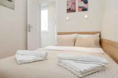 a white bedroom with two beds with towels on them at City Break Apartments Klishe Zen in Belgrade