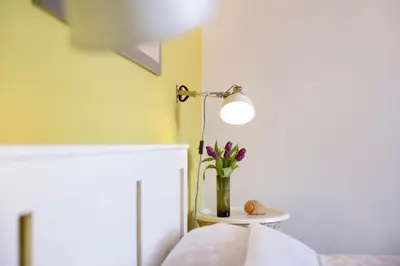 a vase of flowers on a table with a lamp at Apartment Downtown Atelje in Belgrade