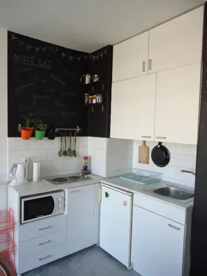 a kitchen with white cabinets and a blackboard on the wall at Apartment Downtown Atelje in Belgrade